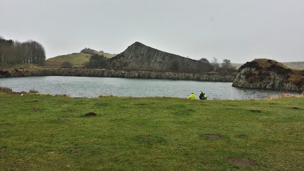 Baggersee mit Polizeitauchern, im Hintergrund der Steinwall: Hadiran's Wall