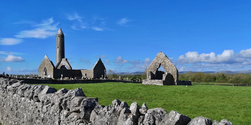 Kilmacduagh mit Rundturm und Kathedrale, im Vordergrund die Kirche von St. John the Baptist